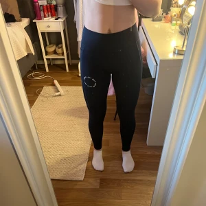 Marinblåa träningstights - Snygga marinblåa leggings med ett tryck på låret. De är högmidjade och har en tight passform, perfekta för träning eller en aktiv vardag. Materialet är stretchigt och bekvämt. Storlek S, köpta på Zalando men vet inte märket.