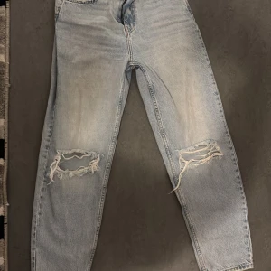 Ljusa jeans med slitningar  - Snygga ljusa jeans med slitningar på knäna. De har en klassisk femficksdesign och en bekväm passform. Perfekta för en avslappnad stil.