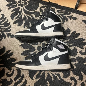 Svarta och vita Nike Air Jordans - Snygga Nike Air Jordans i svart och vitt med klassisk design. Skorna har snörning och en hög siluett som ger ett sportigt intryck. Perfekta för dig som vill ha en stilren look med en ikonisk touch. Storlek 42.5