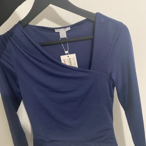 Blå omlottklänning från Amisu - Snygg blå omlottklänning från New yorker i en härlig nyans. Klänningen har långa ärmar och en elegant omlottdesign som ger en stilren look. Perfekt för att skapa en chic outfit.