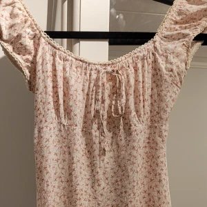 Blommig klänning från Pimkie - Rosa klänning från Pimkie med ett sött knytband vid bröstet. Klänningen har en dragkedja i ryggen. Perfekt för en somrig look! Stor ingen storlek men skulle gissa på S. Dragkedja kan va lite seg men e inget som märls