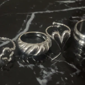 Snygga silverringar i olika designer - Säljer dessa 4 ringar som är i rostfritt stål ( man kan tvätta händerna och ha dem i vatten utan att de rostar) hjärtat och fyrklöver ringen är justerbara och dem andra är i strl 16mm.
