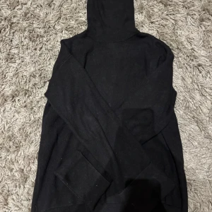 Svart stickad polotröja - Säljer en svart polotröja med långa ärmar. Perfekt för kyliga dagar och enkel att matcha med olika outfits. Tröjan har en klassisk design med ribbade detaljer vid ärmslut och nederkant.