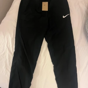 Nike träningsbyxor dri-fit  - Hej alla! Jag har dessa snygga svarta Nike Dry Fit träningsbyxor som jag vill sälja då jag köpte i fel storlek och retur perioden har löpt ut. Med prislappen och kvittot kvar kan du vara säker på att du får en kvalitetsprodukt. Dessa mjukisar är perfekta för träning eller avslappnade dagar. Kontakta mig om du har några frågor. Bara seriösa köpare tack! 