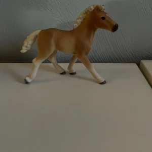Schleich häst  - Säljer en detaljerad brun hästfigur med vit man och svans. Figuren har en naturlig pose och är perfekt för samlare eller som dekoration. Den är tillverkad i plast och har en realistisk design.