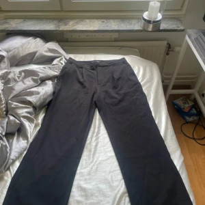 Svarta byxor från 157 - Snygga svarta byxor från 157 i storlek L. De har en klassisk design med dragkedja och knapp framtill. Aldrig använda 
