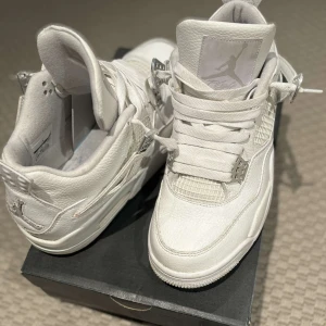 Vita jordan 4 retro sneakers  - Snygga vita Nike Air Jordans med klassisk design och snörning. Skorna har en stilren look med detaljer i vitt och en ikonisk logga på plösen. Perfekta för den som vill ha en tidlös sneaker i garderoben. Bra sick 