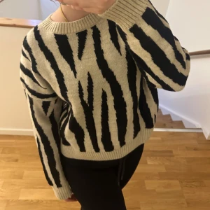 Zebra mönstrad tröja - Säljer en snygg beige och svart tröja från MANGO med zebramönster. Tröjan är stickad och har långa ärmar med ribbade muddar. Endast använd en gång! Storlek M men passar XS/S