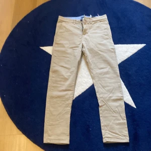 Beige skinny chinos från H&M - Snygga beige skinny byxor från H&M med stretch för extra komfort. Byxorna har en urban stil och är perfekta för en avslappnad look. Tillverkade i bomull med en liten del elastan för flexibilitet.