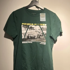 Grön t-shirt med Formel 1-tryck från Firefly - Snygg grön t-shirt från Firefly i ekologisk bomull. Den har ett coolt Formel 1-tryck med texten 'Grand Prix Monaco Since 1929'. Perfekt för racingfans! 🏎️
