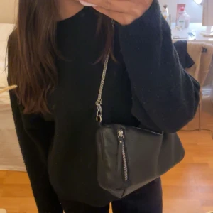 Svart axelväska med dragkedja - Snygg svart väska med flera fack. Väldigt rymlig och jättebra skick. Väskan är från surifrey men har bytt ut själva bandet. Kom privat för fler bilder!