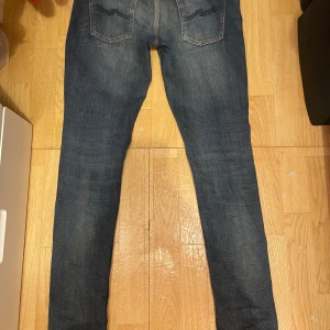 Mörkblå jeans från Nudie Jeans - Snygga mörkblå jeans från Nudie Jeans med en klassisk femficksdesign. De har en straight passform och är tillverkade i slitstarkt denim. Perfekta för en avslappnad stil.