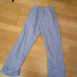 Ljusblå mjukisbyxor med snörning - Säljer ett par ljusblå mjukisbyxor med elastisk midja och snörning. Byxorna har en avslappnad passform och är perfekta för en bekväm dag hemma. De har raka ben och är tillverkade i ett mjukt material.De är storlek 146-152