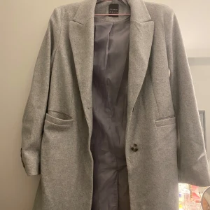 Ljusgrå kappa - Fin grå kappa. Passar väldigt bra tillsammans med jeans och kostymbyxor. Använd ett fåtal gånger, väldigt bra skick 