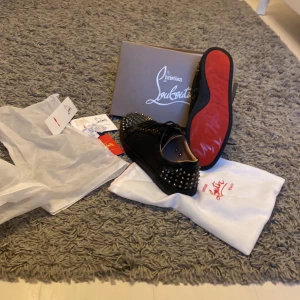 Svarta sneakers med nitar från Christian Louboutin svesta 2 - Snygga svarta sneakers från Christian Louboutin med ikoniska röda sulor och nitar över hela ovandelen. Skorna kommer med originalförpackning och dustbag. Perfekta för den som vill sticka ut med stil.dem är rätt så stora men dem passar som en 46or