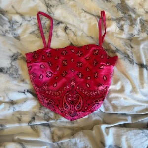 Rosa bandanamönstrad topp - Säljer en rosa bandanamönstrad topp. Toppen har smala axelband och en knytning i ryggen. Perfekt för sommardagar med sin lätta och luftiga design.