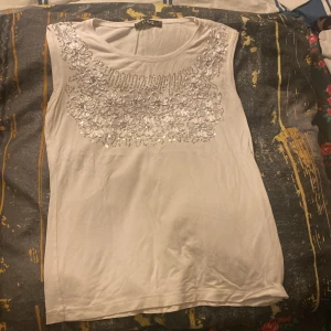 Vit ärmlös topp från D&G - Säljer en stilren vit ärmlös topp från D&G med vackra blommiga broderier och paljetter på framsidan. Köpt secondhand men aldrig blivit använd av mig. Toppen är i ett mjukt och bekvämt material 🤍