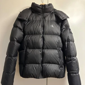 Dunjacka herr S - Calvin Klein dunjacka använd en vinter. Fint skick! Lagning som knappt syns i verkligheten,strax ovanför märket på ärmen - se bild. 