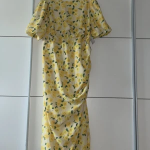 Blommig gul klänning från Bubbleroom - Superfin gul klänning från Bubbleroom med blommigt mönster. Den har korta ärmar och en söt knytning i ryggen. Perfekt för sommarens fester eller en härlig dag i solen. Klänningen är i ett lätt och luftigt material som gör den bekväm att bära hela dagen. Men har även en fin slits  Kan mötas upp nära Malmö 