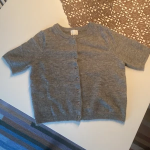 Grå kofta från H&M - Säljer en mysig grå kofta från H&M i storlek M. Den har korta ärmar och knäpps med stilrena knappar framtill. Perfekt för både vår och höst och passar till det mesta! Säljer pga att den inte riktigt passade mig, aldrig använd utan har bara testat den! Nypris 200, mitt pris 170!
