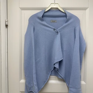 Ljusblå kofta från Hunkydory - Säljer en superfin ljusblå kofta från Hunkydory ❄️ Den är stickad och har en unik omlott-design med en knapp framtill. Perfekt för både vår och höst när du vill ha något mysigt men ändå stilrent❄️Passar fint till jeans !