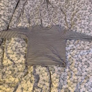 Randig tröja från Kappahl - Säljer en superfin randig tröja från Kappahl i storlek 134/140. Den är svart och vit med långa ärmar och har en söt volangdetalj. Perfekt för både vardag och skola!