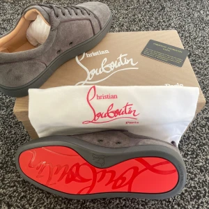 Grå mockaskor från Christian Louboutin - Säljer ett par snygga grå mockaskor från Christian Louboutin. De har den ikoniska röda sulan och är i nytt skick. Perfekta för både vardag och fest med sin stilrena design och bekväma passform. Kommer med originalkartong och dustbag.