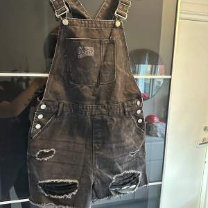 Säljer ett par coola svarta jeansshorts med hängslen från Denim Co. De har slitna detaljer och knappar på sidorna. Perfekta för en avslappnad sommarlook eller festival. 🖤