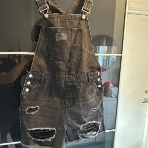 Svarta jeansshorts med hängslen från Denim Co. - Säljer ett par coola svarta jeansshorts med hängslen från Denim Co. De har slitna detaljer och knappar på sidorna. Perfekta för en avslappnad sommarlook eller festival. 🖤