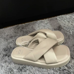 Beige sandaler från Vox - Säljer ett par superbekväma beige sandaler från Vox i storlek 39. De har en snygg korsad design på ovansidan och en tjock sula för extra komfort. Perfekta för sommardagar! 🌞
