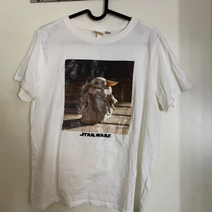 Vit Star Wars t-shirt med Baby Yoda st S - Säljer en vit t-shirt från H&M med ett tryck av Baby Yoda från Star Wars. T-shirten är kortärmad och i bomull, perfekt för alla Star Wars-fans. Den är i storlek S och har en normal passform. Perfekt för vardagsbruk eller som en cool present! Nyskick! Jul???