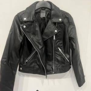 Svart skinnjacka - En svart skinnjacka (fejk skinn). Använd flera gånger men inga skavanker.