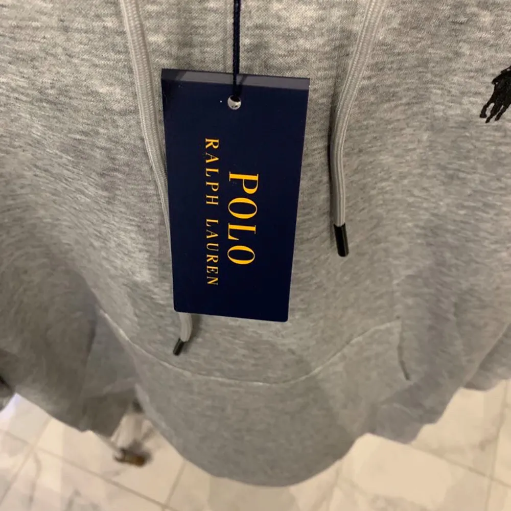 Säljer en snygg och bekväm grå hoodie från Polo Ralph Lauren. Den har en klassisk design med en liten broderad logga på bröstet och en praktisk magficka. Perfekt för både vardag och chill. Huvan har justerbara snören för extra komfort. Skick 10/10. Tröjor & Koftor.