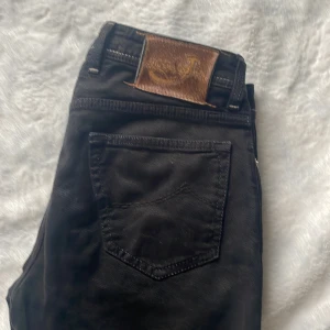 Svarta jeans från Jacob Cohen - Säljer ett par snygga svarta jeans från Jacob Cohen. De har en klassisk femficksdesign med en stilren broderad detalj på myntfickan. Jeansen har knappar i gylfen och en läderpatch bak. Perfekta för både vardag och fest!