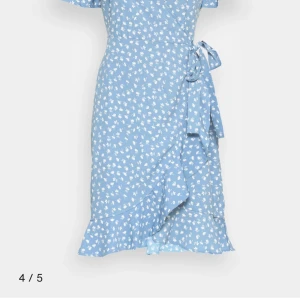 Blommig omlottklänning från ONLY - Säljer en superfin blommig omlottklänning från ONLY. Den har en v-ringad design med korta ärmar och ett färgglatt blommönster i lila, orange och vitt på en svart bakgrund. Perfekt för vår och sommar! 🌸endast använd ett fåtal gånger. Obs! Inte samma färg som på första bilden men jag tror att modellen är samma!💞