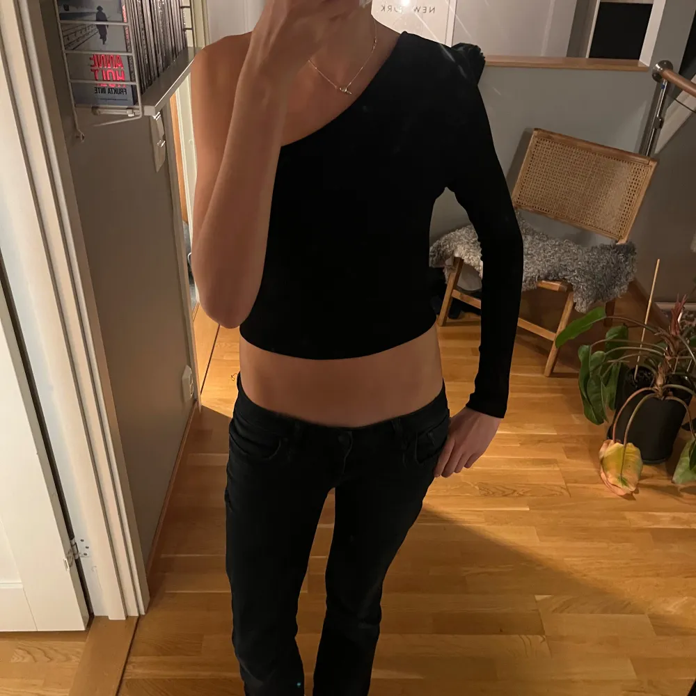 Säljer en snygg svart oneshoulder topp från NA-KD i storlek XS. Toppen är ribbad och har en tight passform, perfekt för festliga tillfällen. Den är i mycket bra skick och ger en stilren look med sin enkla design.. Toppar.