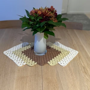 Virkad duk  - Säljer en handgjord virkad duk i vackra jordnära färger. Den har ett fyrkantigt mönster med brunt, beige och vitt garn. Perfekt för att ge ditt bord en hemtrevlig och stilren känsla. Passar bra till både vardag och fest! 