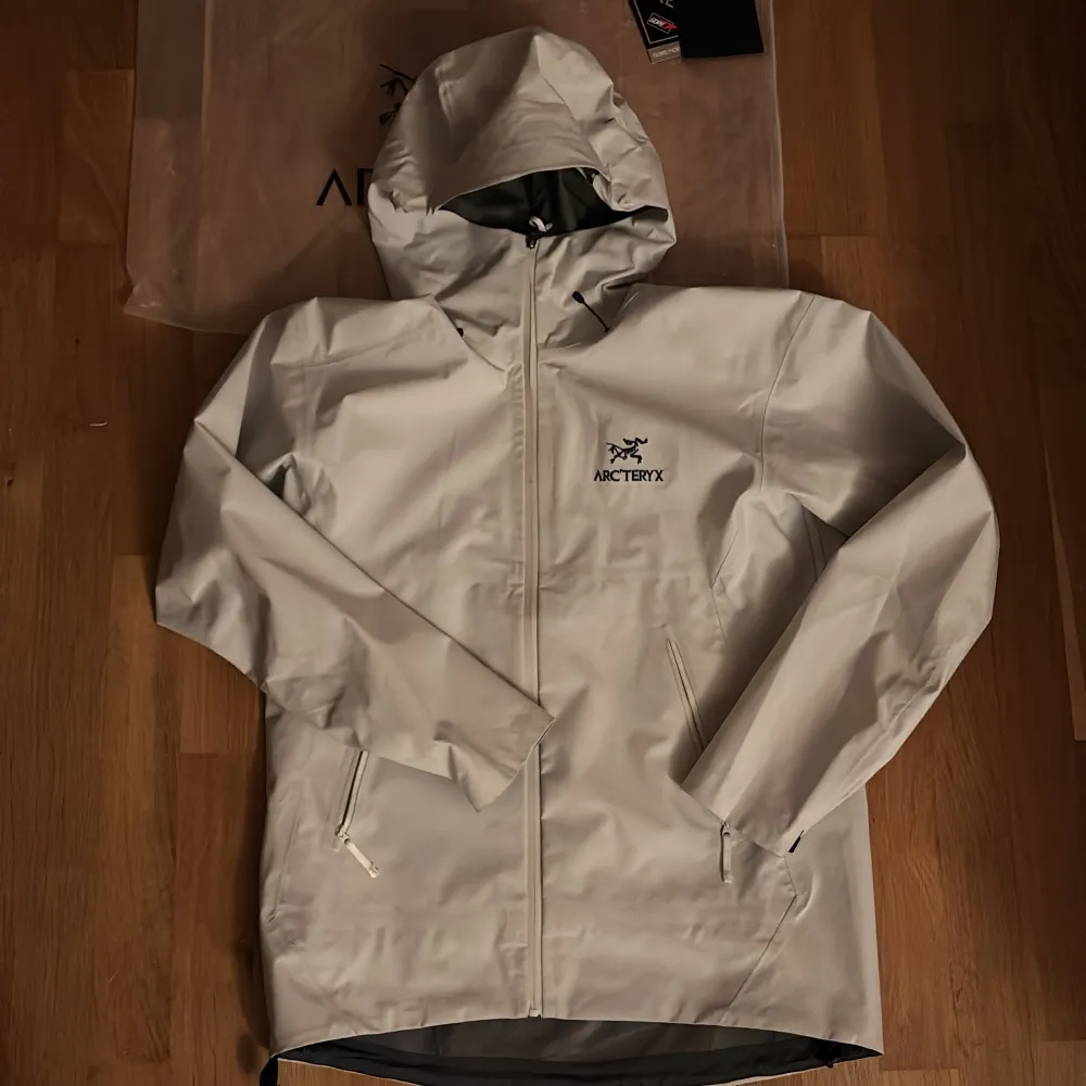 Säljer en snygg vit regnjacka från Arc'teryx i storlek L/XL. Jackan är tillverkad i GORE-TEX-material och har en praktisk huva. Perfekt för regniga dagar med sin vattentäta design och dragkedja framtill. Den är i nytt skick och redo för äventyr! 🌧️. Jackor.