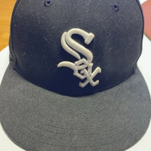 Svart keps från New Era - Säljer en svart keps från New Era med en broderad logga på framsidan. Kepsen är i bra skick använd fåtal gånger. 