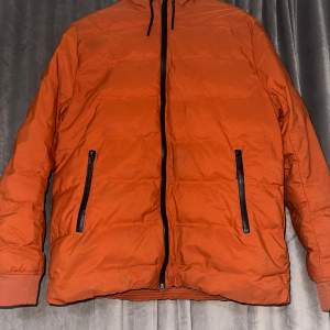 Säljer en snygg orange pufferjacka från H&M i storlek M. Jackan har en dragkedja framtill och två praktiska fickor med dragkedjor. Perfekt för höst och vinter med sin varma och bekväma design. Den har långa ärmar med ribbade muddar för extra komfort. Passar både till vardags och lite mer avslappnade tillfällen.