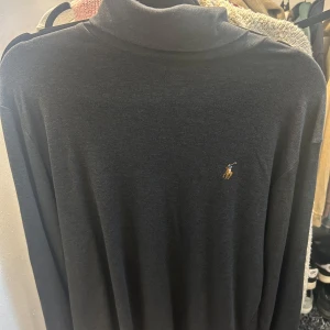 Mörkgrå polotröja från Ralph Lauren - Säljer en stilren mörkgrå polotröja från Ralph Lauren. Tröjan har en klassisk design med en broderad logga på bröstet. 