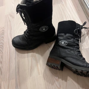 Svarta boots från Rieker  - Säljer ett par svarta Rieker boots i mycket bra skick. De är fodrade med mjukt material för extra värme och har både snörning och dragkedja för enkel på- och avtagning. Perfekta för höst och vinter!  Sparsamt använda 