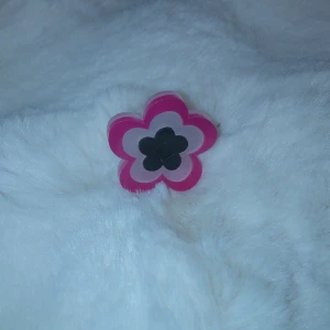 Blommig ring i plast - Superfin ring i form av en blomma med lager i rosa, svart och vitt. Den är gjord av plast och har en cool, retro känsla. Perfekt för att liva upp vilken outfit som helst med en färgglad touch! Passar bra till både vardag och fest.