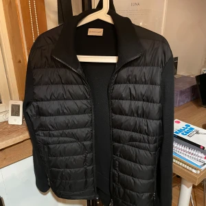Svart jacka från Moncler - Säljer en snygg svart jacka från Moncler i mycket bra skick. Jackan har en quiltad design med dragkedja och långa ärmar. Perfekt för höst och vår, och den är gjord i ett bekvämt syntetmaterial. Passar både till vardags och lite finare tillfällen. Har inte använt den så mycket har bara haft den ungefär i 3 månader 