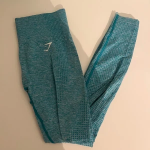 Turkosa träningstights från Gymshark - Säljer ett par snygga turkosa träningstights från Gymshark. De är i ett stretchigt och bekvämt material, perfekt för gymmet eller yoga. Tightsen har en hög midja och en diskret logga på sidan. De är i mycket bra skick och redo för nya äventyr!