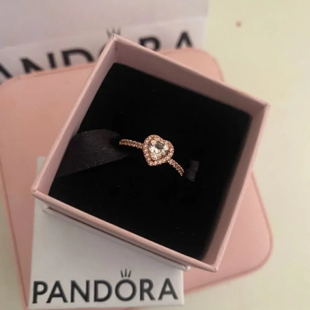 Säljer en superfin ring från Pandora med en glittrig hjärtformad sten i mitten. Ringen är i roséguld och har små gnistrande stenar runt om. Perfekt för speciella tillfällen eller som en kärleksfull present. Kommer i originalförpackning.. Accessoarer.