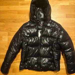 Svart pufferjacka från Save The Duck - Säljer en snygg mörkblå pufferjacka från Save The Duck. Skulle dock säga att den lutar mer mot svarta hållet. Jackan är i mycket bra skick och perfekt för vintern. Den har en dragkedja framtill och är quiltad för extra värme. Tillverkad i ett mjukt syntetiskt foder och har en mkt skön huva. Perfekt för kalla dagar!  Köpt för 3800 förra vintern mvh Theo.