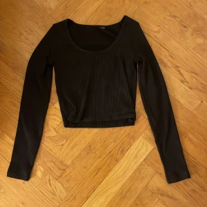 Svart ribbad långärmad topp - Säljer en stilren svart ribbad topp med långa ärmar. Perfekt för både vardag och fest. Toppen har en bekväm passform och är gjord i ett mjukt material som känns skönt mot huden. Passar utmärkt till jeans eller kjol för en chic look. Köptes på hm för ett år sedan för 350 kr och är använd ganska mycket men har fortfarande inget slitage. 💞