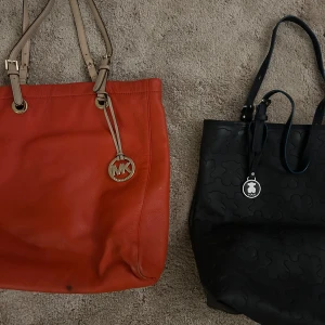 Orange  skinnväska från Michael Kors & Svart Teddy bag från Tous - Säljer en snygg  skinnväska från Michael Kors med beige axelremmar och ett klassiskt MK-hänge. Väskan har en praktisk dragkedja inuti och är perfekt för både vardag och fest. Den behöver en touch up! Den svarta har rosa foder & sparsamt använd