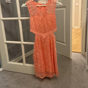 Persikofärgad spetsklänning från Luc & Ce - Säljer en superfin persikofärgad klänning från Luc & Ce i storlek M. Klänningen är ärmlös med vacker spets och en öppen ryggdetalj och sidodetalj Den har en dragkedja i ryggen för enkel påklädning. Klänningen är i stl M men passar även S